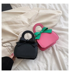 Detail of mini handbag with bow decoration and metal bead chain in black and pink