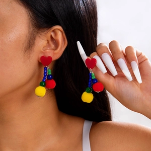 Detail of colorful beaded tassel earrings featuring red heart studs and soft pom-poms