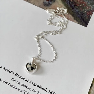 Detail of S925 silver heart necklace with natural zebra stone on art book background