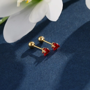 Macro shot of triangle red zircon earrings with gold screw backs on blue surface