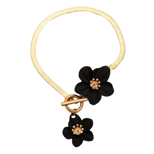 Detail of gold snake chain necklace featuring two black flower pendants and OT clasp toggle