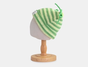 Close-up of green and yellow striped knit hat with a bow detail and side label