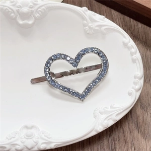 Detail of silver heart hair clip with light blue crystals on white ceramic tray