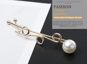 Close-up of golden alloy hairpin with twisted lines, round ring and white faux pearl detail