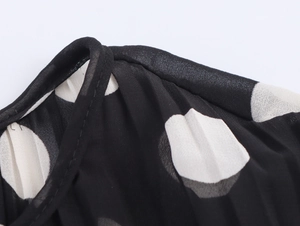 Detail view of polka dot chiffon dress showing shoulder stitching and fabric texture