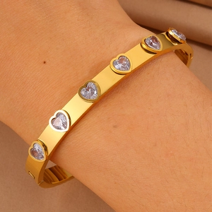 Détail d'un bracelet doré avec zircon en forme de cœur et fermoir à charnière