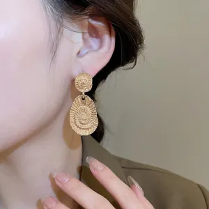 Golden oval vortex metal drop earrings featuring fine textured swirl geometric patterns
