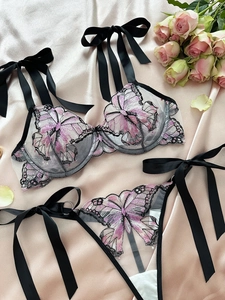 Detail of pink butterfly embroidery on black mesh bra with decorative satin bows