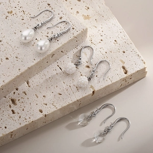 Gros plan détaillé de trois styles de boucles d'oreilles pendantes sur pierre beige