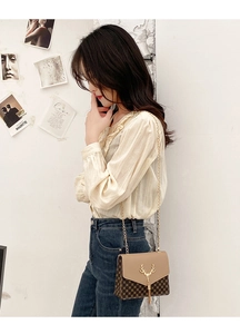 Crossbody bag with khaki leather flap, monogram pattern, and gold deer head hardware