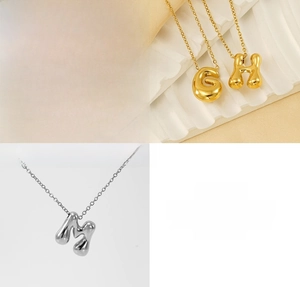 Detail of 3D bubble letter pendants in gold and silver polished stainless steel