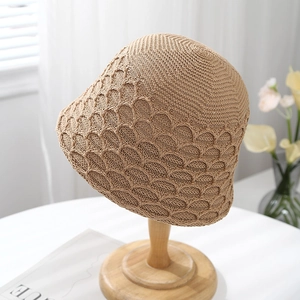 Handmade hollow knit bucket sun hat for women in warm khaki on a wooden stand