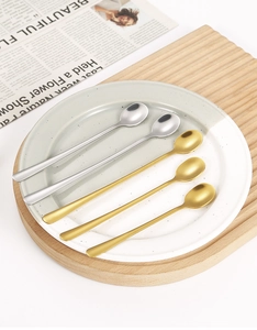 Detailed view of silver and golden stainless steel coffee spoons on a ceramic plate