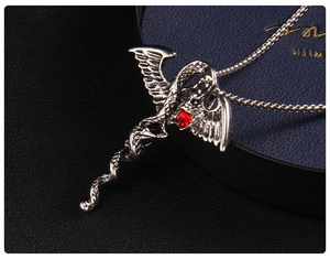 Gros plan du pendentif gothique en forme d'ailes d'ange avec gemme rouge et motif dragon