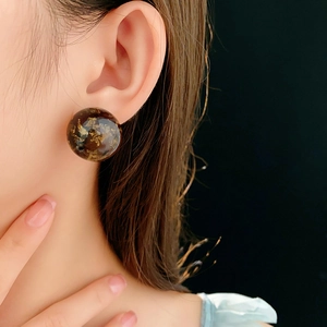 Macro shot of amber resin stud earrings with gold foil on a model for a vintage look