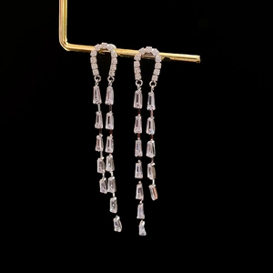 Detailed macro view of U-shaped tassel earrings featuring micro-set cubic zirconia stones