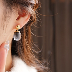 Close-up of elegant 18K gold-plated earring with a translucent smoky gray resin pendant