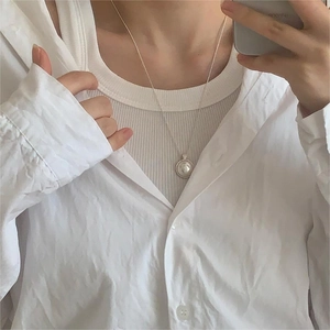 Close-up of a minimalist silver chain necklace with a round pearl pendant worn by a model
