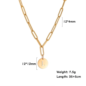 Detail view of gold round pendant with letter L and dimensions on paperclip chain