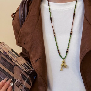 Macro detail of a gold plated poodle pendant on a vintage beaded tiger eye necklace