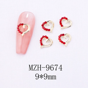 Macro detail of 9x9mm heart nail charm with gold hollow frame and red rhinestones