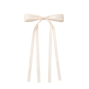 Détail d'un nœud de cheveux en satin beige avec de longs rubans sur fond blanc