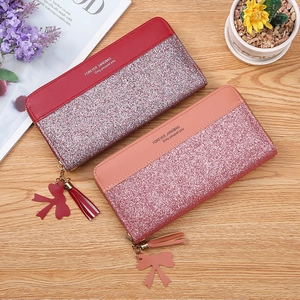 Detail of long zipper wallets with glitter finish, tassel zippers and bow charms