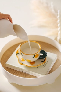 Close-up of hand-painted lemon pattern ceramic coffee cup being filled with fresh milk