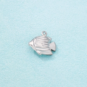 Macro shot of silver hollow fish pendant with detailed scales on light blue background