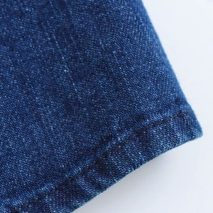 Dettaglio macro della trama in denim blu scuro e cuciture overlock di alta qualità