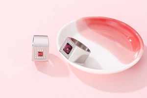 Close-up of thick stainless steel rings with square red zircon stone on a ceramic plate