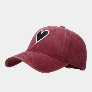 Detail of vintage washed cotton baseball cap in burgundy with heart embroidered patch