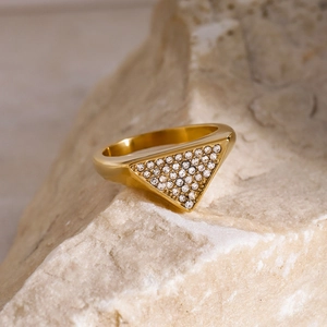 Macro detail of gold-plated triangle ring with pavé zircons on textured stone