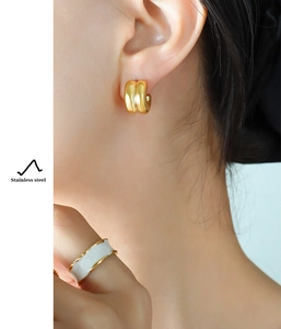 Detail of stainless steel double C earrings and white irregular ring on a model