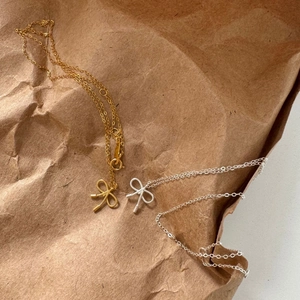 Top view of gold and silver bow necklaces with twist texture on brown paper
