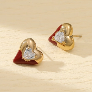 Close-up of heart-shaped earrings with red enamel, gold plating and zircon inlay