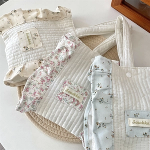 Close-up of three quilted floral wrist bags with ruffled edges and Sozakka label