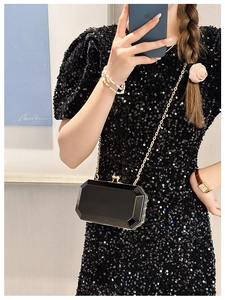 Mirror selfie showing black acrylic clutch bag with gold chain and sequins dress