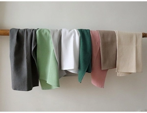 Detail showing various colors of waffle weave cotton towels hanging on a wooden rod