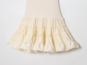Detailed view of cream-colored layered ruffles and textured fabric on women's dress