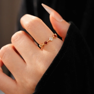 Macro detail of 18k gold-plated ring featuring zircon stones and red enamel flower design