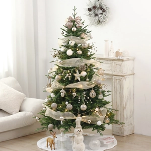 Detailed view of champagne and white ornaments on a lit mini musical Christmas tree