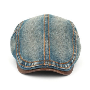 Detail of washed denim newsboy cap with orange contrast stitching and leather brim edge