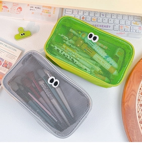 Detail of green and gray mesh storage bags with cute eye designs on a desk setup