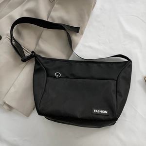 Detail of black nylon messenger bag with adjustable strap on a light suit jacket