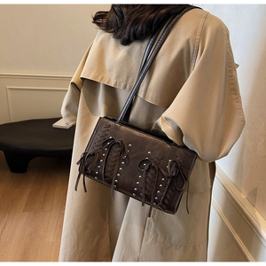 Close-up of dark brown suede shoulder bag with metal rivets and leather bow detail