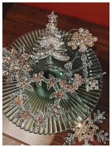 Macro shot of clear acrylic Christmas ornaments with rose gold sequins in a green glass dish