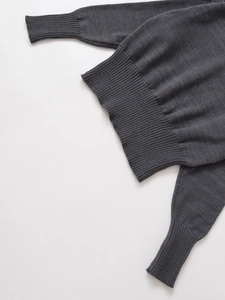 Dettaglio maglione in maglia grigio scuro con polsini a coste fini e trama elastica fine