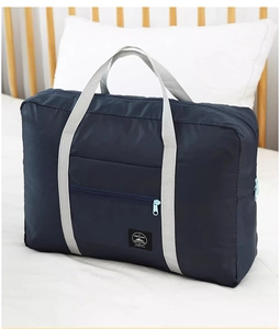 Detail of waterproof nylon travel bag with gray handles and zipper pocket in a bedroom setting