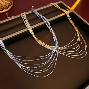 Detail of layered gold and silver snake bone necklaces in a black display gift box